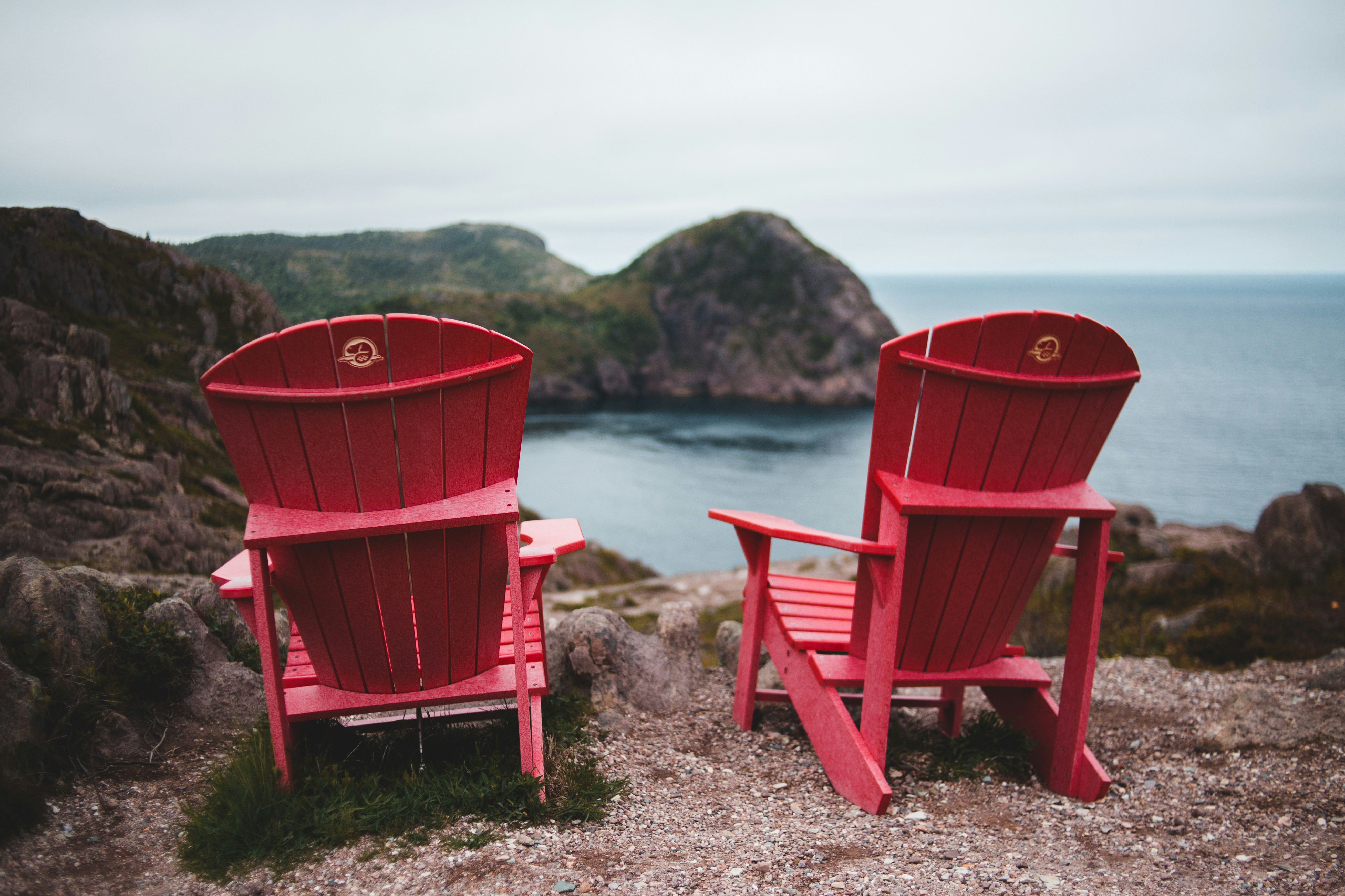red wooden rocking chair on seashore during daytime